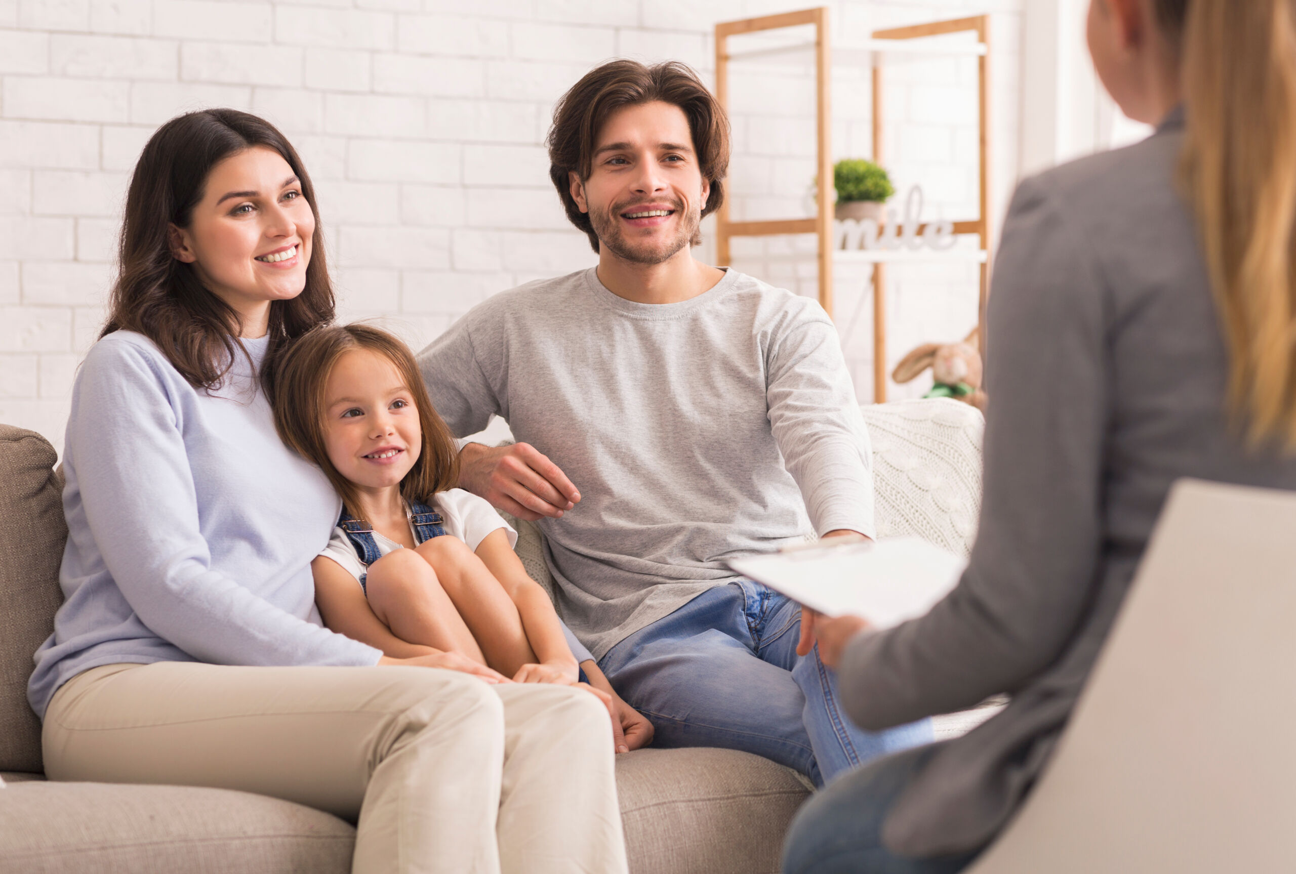 Parents With Little Daughter Sitting At Psycholigist’s Office After Successful Therapy
